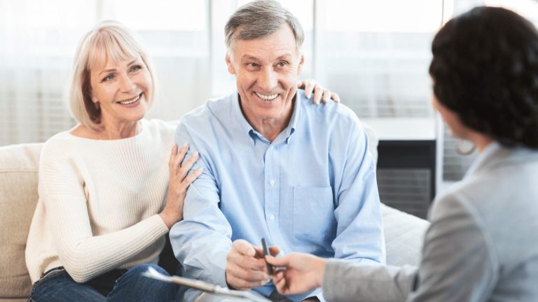happy mature couple talking to financial advisor at home