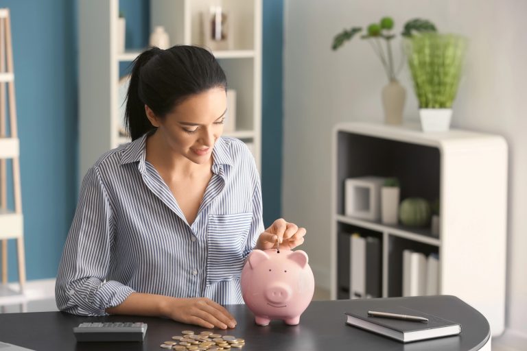 woman inserting coins into a pink piggy bank, saving and financial planning