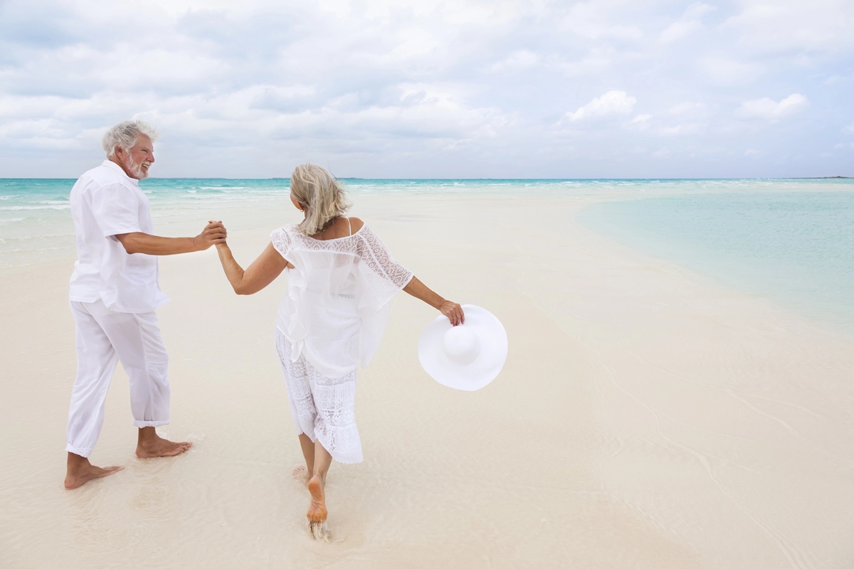 happy mature couple walking outdoors together on tropical beach